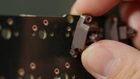 Insert stabilizer clips into the larger holes and pivot the threaded end into the smaller holes. It should sit completely flat on the PCB.